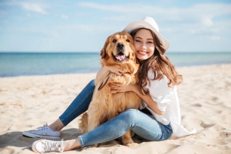 女人在沙滩上拥抱她的狗